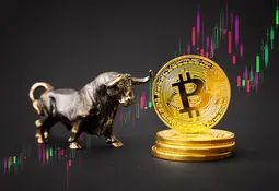 Stapel von Bitcoin-Münzen mit einer Bullenfigur aus Metall daneben. Im Hintergrund ist eine Candlestick-Chart mit Aufwärtstrend angedeutet.